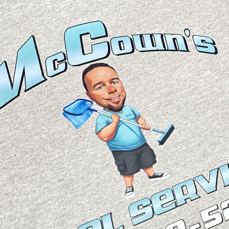 Grey crew tee printed with a pool service logo and a custom cartoon of the owner
